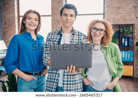 Friendly group of young professionals collaborating with a laptop in a modern shared workspace office