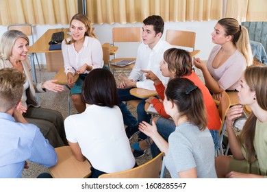 Friendly group of young students studying in university with female tutor 