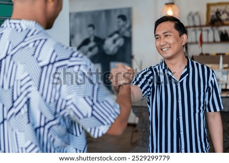 A friendly handshake between two welldressed men in stylish shirts at a lively cafe