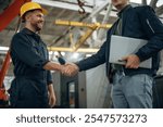 Friendly handshake. Two male factory workers are in the warehouse.