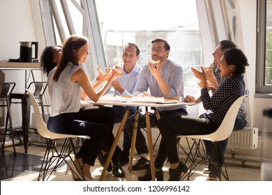 Friendly happy diverse team workers talking laughing eating pizza together in office, cheerful workers staff group chatting sharing meal enjoying having fun at work, good relations at lunch break