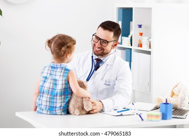 Friendly Happy Male Doctor Pediatrician With Patient Child Girl In His Office At The Clinic