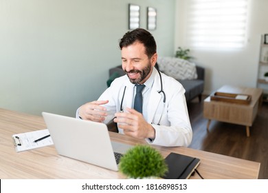 Friendly Hispanic Doctor Working From Home And Talking To A Patient In A Video Call