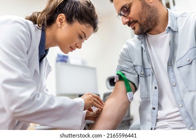 Friendly Hospital Phlebotomist Collecting Blood Sample From Patient In Lab. Preparation For Blood Test By Female Doctor Medical Uniform On The Table In White Bright Room