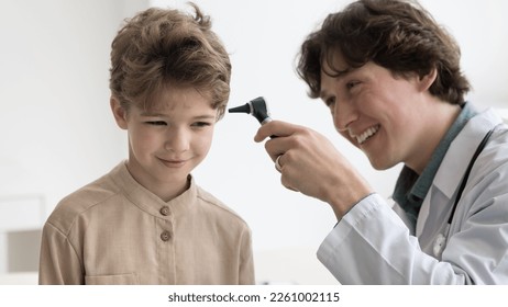 Friendly kids doctor examining ear of boy, holding otoscope, using medical tool, checking child for flu, virus, infection, smiling. Positive little patient visiting otolaryngologist - Powered by Shutterstock