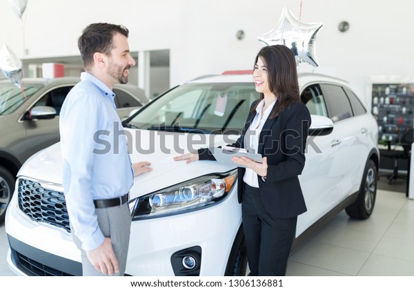 Friendly and knowledgeable adviser showing car to\
businessman as per his\
desire