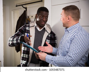 Friendly landlord visiting tenant apartment, signing agreement with positive man