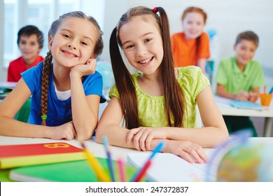 Freundliche kleine Mädchen, die auf Unterricht mit Kamera schauen