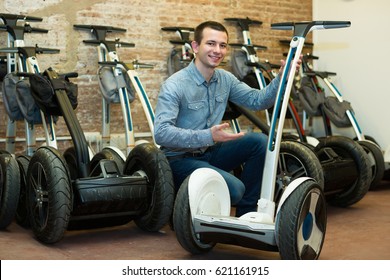 Friendly male consultant in front of segways at rental agency