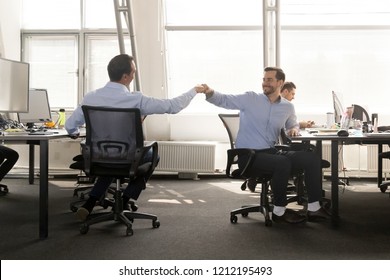 Friendly Male Coworker Buddies Fist Bumping At Work Celebrate Good Teamwork Result, Happy Smiling Colleagues Share Success Motivated By Great Relations, Corporate Culture Help Support Respect Concept