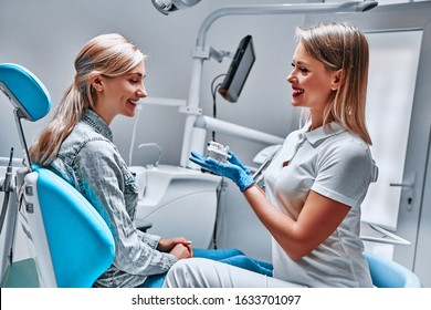 Friendly Male Dentist Showing Teeth Model To His Patient. Side View