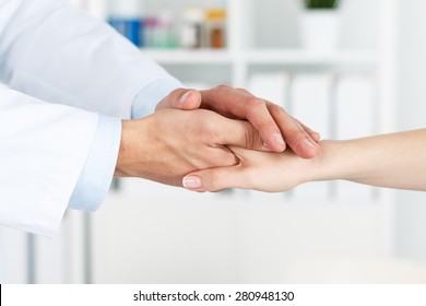 Friendly Male Doctor's Hands Holding Female Patient's Hand For Encouragement And Empathy. Partnership, Trust And Medical Ethics Concept. Bad News Lessening And Support. Patient Cheering And Support