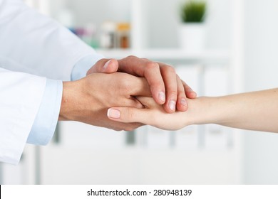 Friendly Male Doctor's Hands Holding Female Patient's Hand For Encouragement And Empathy. Partnership, Trust And Medical Ethics Concept. Bad News Lessening And Support. Patient Cheering And Support