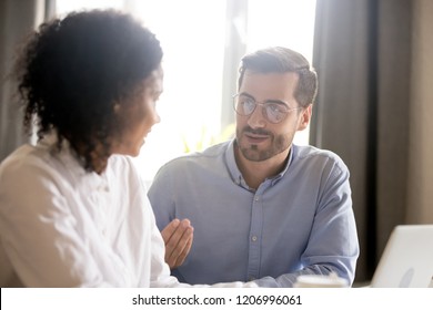 Friendly male mentor teacher training employee explaining african-american female intern student teaching new project, diverse colleagues talking in office, working together, help coaching concept