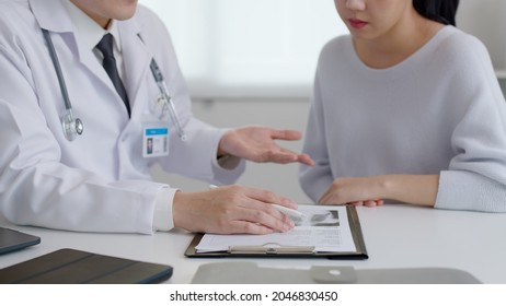 Friendly Medic Service People Or Asia Male Help Talk Discuss Of Medical Exam Record Test Result At Clinic Office Desk. Young Sad Serious Stress Woman Visit, Follow , Listen, See Doctor At Hospital.