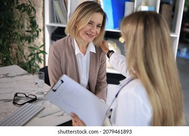 Friendly Middle Aged Female Doctor Encouraging, Supporting Patient After Medical Examination