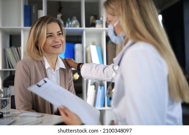 Friendly Middle Aged Female Doctor Encouraging, Supporting Patient After Medical Examination