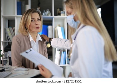 Friendly Middle Aged Female Doctor Encouraging, Supporting Patient After Medical Examination