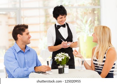 friendly middle aged waitress taking order from customer in restaurant