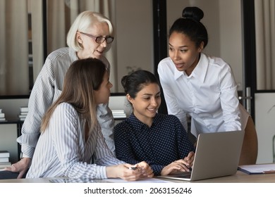 Friendly multiracial corporate female team collaborate at office interacting brainstorming creating sales strategy. Group of four diverse ladies coworkers meet together at workplace to develop project