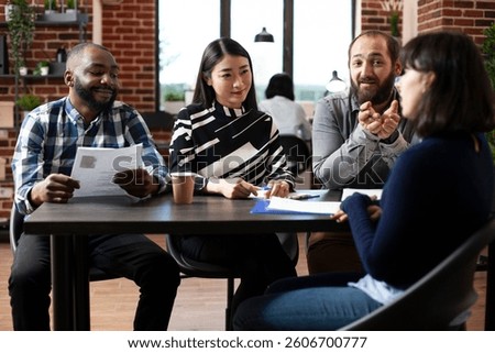 Friendly multiracial HR managers interviewing female candidate at a table, asking about her experience. Diverse recruitment team discussing with potential job applicant. Hiring concept.