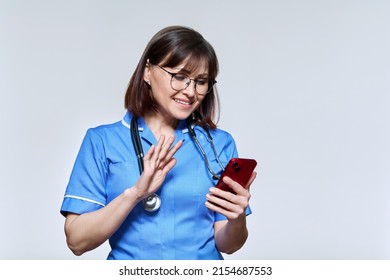 Friendly Nurse Waving Hand At Smartphone Screen, On Light Studio Background