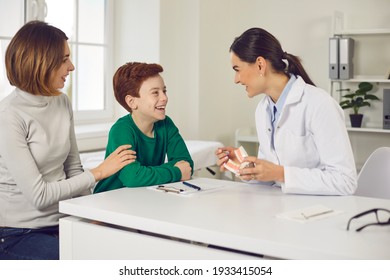 Friendly pediatric dentist consults mother with her young son in the office of a modern dental clinic. Mother and child discuss dental treatment plan. Concept of painless treatment of children's teeth - Powered by Shutterstock