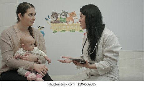 Friendly Pediatrician Doctor Explain Something To Mother With Newborn Baby