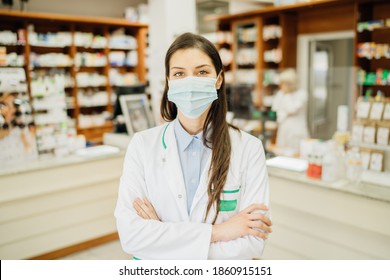 Friendly Pharmacist Working In A Pharmacy Amid Coronavirus Pandemic.Pharmaceutical Health Care Professional Providing COVID-19 Therapy Support.MPharm Ina A Drugstore Wearing A Protective Face Mask