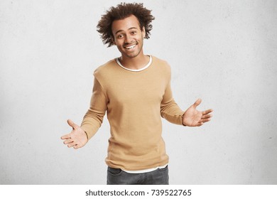 Friendly Positive Dark Skinned Male Gestures, Being Glad To See Old Friend, Going To Embrace, Stands Against White Background With Blank Copy Space. Attractive Excited Mixed Race Man Has Crisp Hair