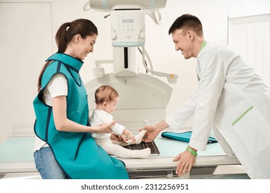 Friendly radiologist preparing child for radiography of lower limb - Powered by Shutterstock