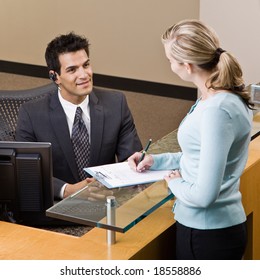 Friendly receptionist greeting woman at front desk