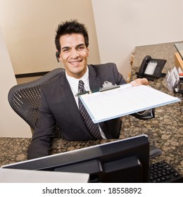 Friendly receptionist offering clipboard and pen at front desk