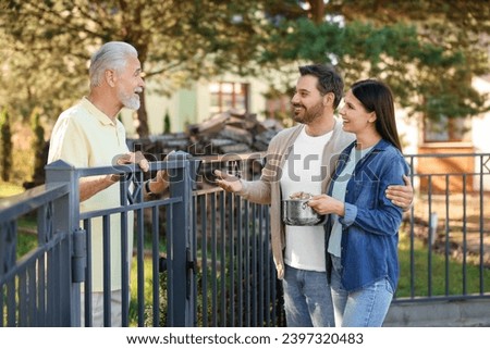 Friendly relationship with neighbours. Happy couple and senior man near fence outdoors