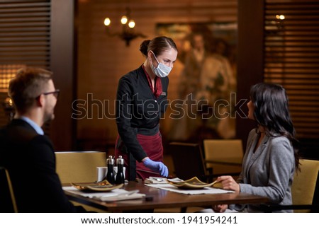Friendly restaurant staff using mask and gloves for protection