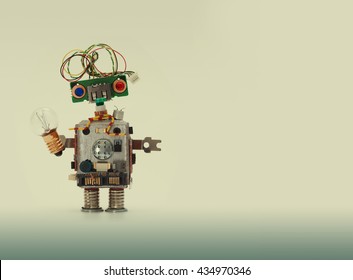 Friendly Robot With Light Bulb. Funny Robotic Toy On Beige Gray Gradient Background. Blank Space