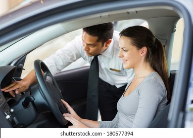 Friendly Salesman Explaining Car Features To Young Female Customer