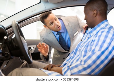 Friendly Salesman Explaining Car Features To Customer