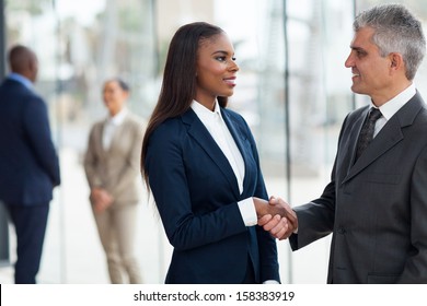 friendly senior businessman handshaking with young businesswoman in office