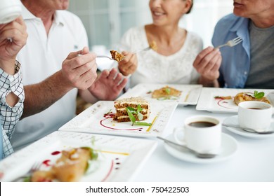 Friendly Senior Companions Eating Homemade Cake With Coffee And Having Talk By Table