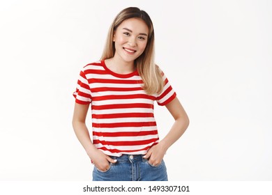 Friendly Shy Cute Blond Asian Female Hold Hands Jeans Pockets Smiling Cheerful Tilt Head Joyfully Keep Conversation Talking Campus Neighbour Standing White Background Modest Asking Out Girl