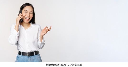 Friendly Smiling Asian Woman Talking On Phone, Girl On Call, Holding Smartphone And Laughing, Speaking, Standing Over White Background