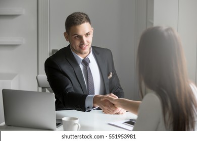 Friendly smiling businessman and businesswoman handshaking over the office desk after pleasant talk and effective negotiation, good relationship, making deal, hiring Business concept photo