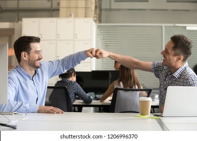 Friendly Smiling Male Colleagues Fist Bumping At Workplace Celebrating Good Teamwork Result Concept, Happy Coworkers Sharing Success Motivated By Collaboration At Work, Respect Or Cooperation Concept