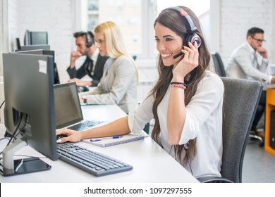 Friendly smiling woman call center operator with headset using computer at office - Shutterstock ID 1097297555