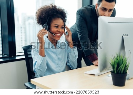 Friendly smiling woman call center operator with headset using computer, Customer service, Call center worker accompanied by her team at office