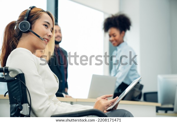 Friendly smiling woman call center operator with\
headset using computer, Customer service, Call center worker\
accompanied by her team at\
office