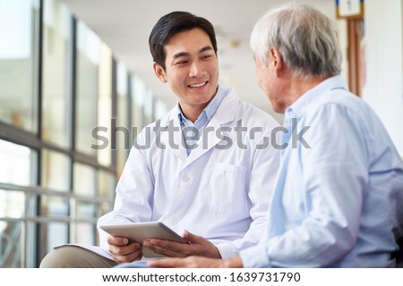 friendly smiling young asian doctor talking and explaining test result to elderly patient in hospital