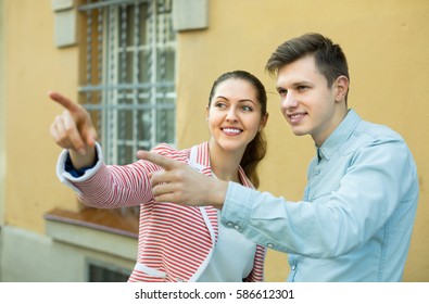 Friendly Smiling Young Brunette Helping Lost Male Tourist To Find Way . Focus On Man
