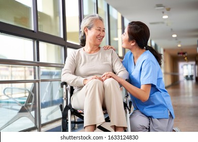 friendly staff caregiver of nursing home talking to asian senior woman in hallway - Powered by Shutterstock